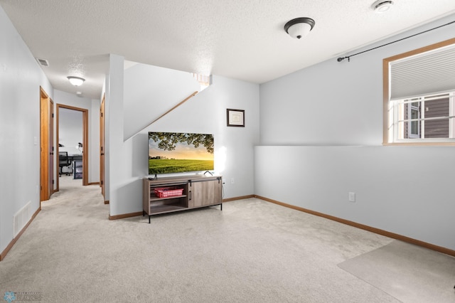 interior space with a textured ceiling, carpet floors, visible vents, and baseboards