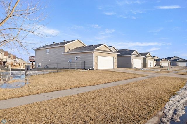 view of front of house with a garage, a residential view, fence, and concrete driveway