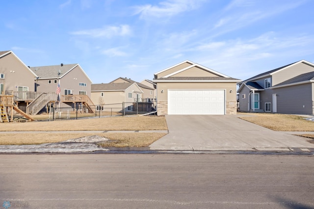 view of front of house with a garage, concrete driveway, stone siding, a residential view, and fence