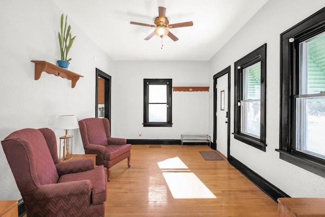 sitting room featuring light wood-type flooring, a ceiling fan, and baseboards