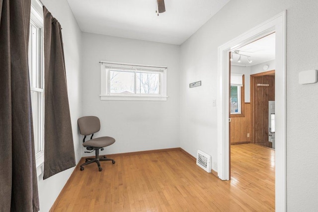 office space featuring baseboards, visible vents, ceiling fan, and light wood finished floors