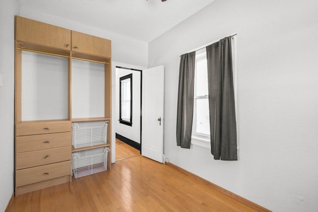 unfurnished bedroom with light wood-type flooring, a closet, and multiple windows