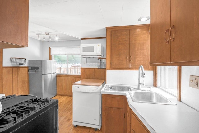 kitchen with white appliances, light countertops, a sink, and brown cabinetry