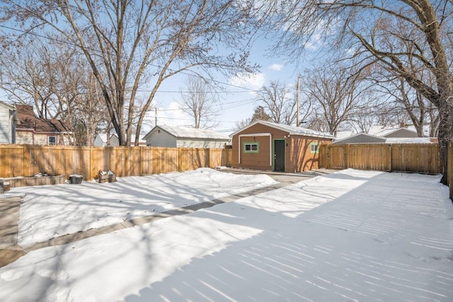 snowy yard featuring an outbuilding and a fenced backyard