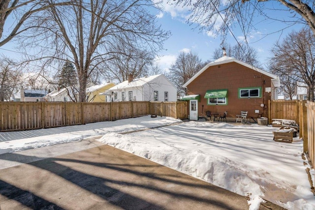 snow covered back of property featuring a fenced backyard