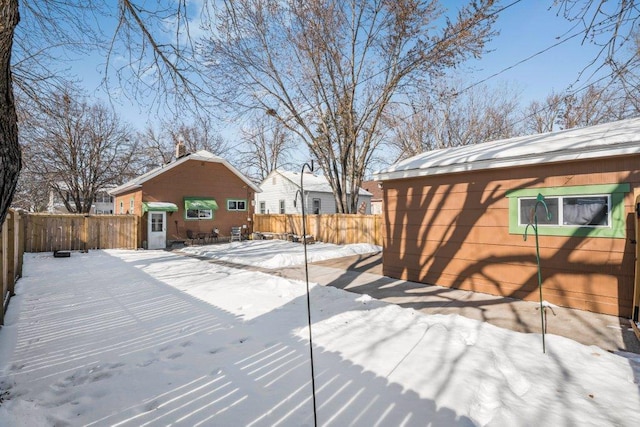 snow covered deck with a fenced backyard