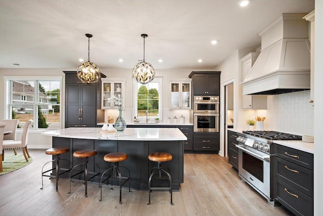 kitchen with a breakfast bar, a spacious island, premium range hood, appliances with stainless steel finishes, and white cabinets