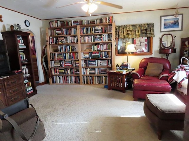 sitting room with ceiling fan, carpet flooring, and crown molding