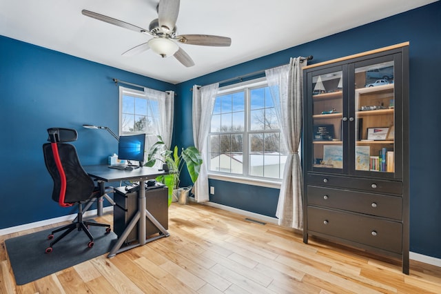 office space with light wood-style floors, visible vents, baseboards, and a ceiling fan