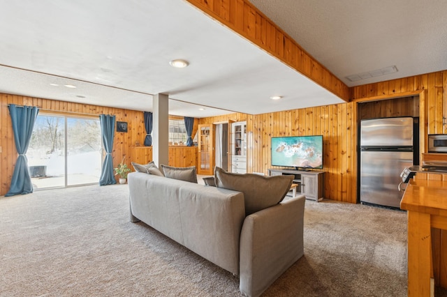 carpeted living room with recessed lighting, beam ceiling, visible vents, and wooden walls