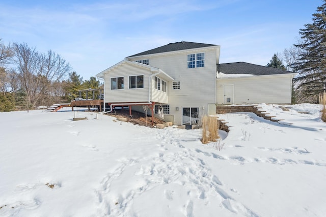 snow covered property featuring a garage, stairway, and a wooden deck