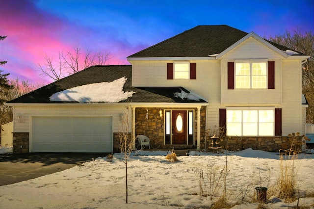 traditional home featuring a garage, stone siding, driveway, and roof with shingles