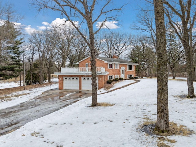 view of front of house featuring driveway, brick siding, and a chimney