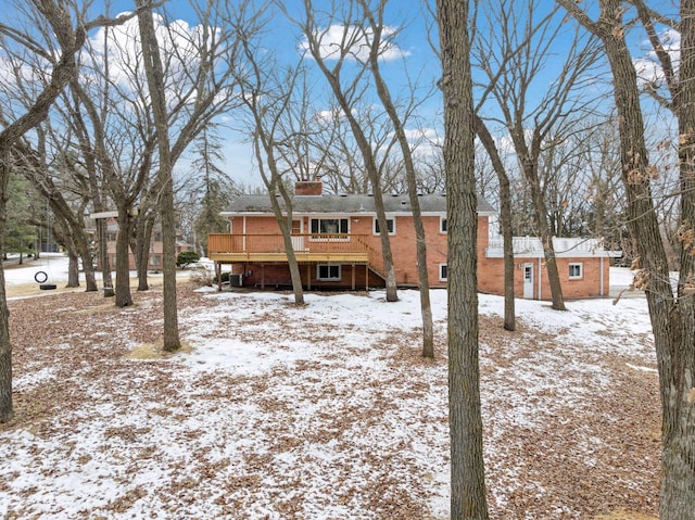 view of front of house featuring brick siding, a deck, and a chimney