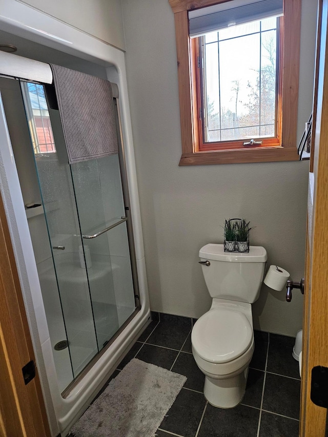 bathroom with a shower with door, toilet, tile patterned floors, and a healthy amount of sunlight