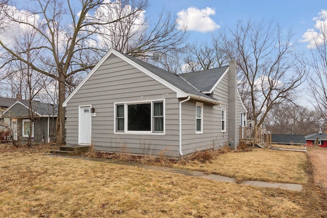 view of front of home with roof with shingles, a chimney, and a front lawn