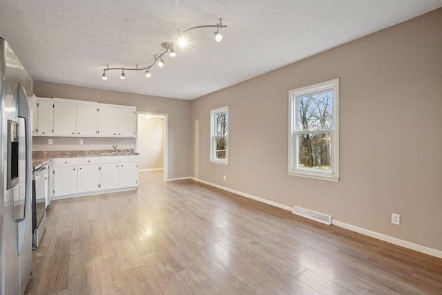 kitchen with baseboards, visible vents, stainless steel fridge with ice dispenser, light wood-type flooring, and white cabinetry