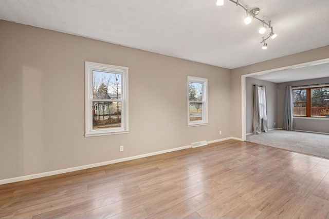 spare room with visible vents, light wood-style flooring, and baseboards