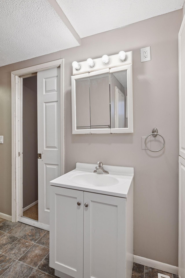 bathroom featuring stone finish floor, vanity, and baseboards