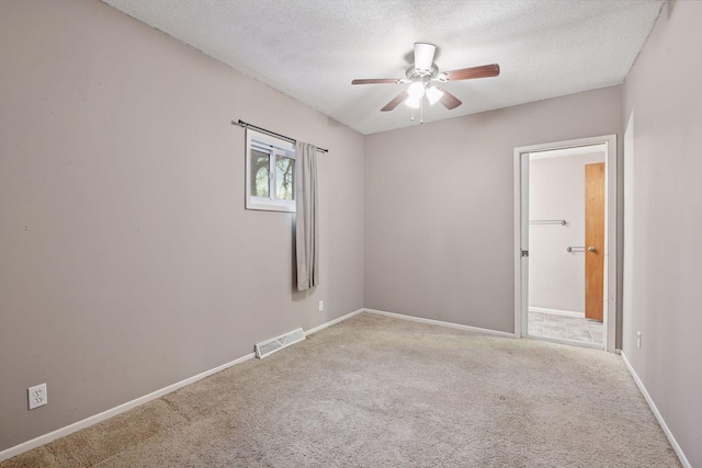 unfurnished room with carpet floors, baseboards, visible vents, and a textured ceiling