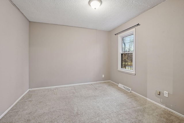 carpeted empty room featuring a textured ceiling, visible vents, and baseboards