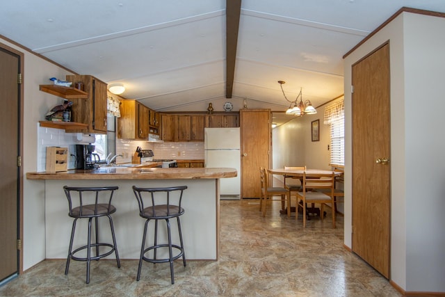 kitchen featuring brown cabinetry, a peninsula, stove, and freestanding refrigerator