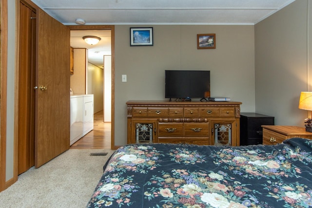 bedroom with washing machine and dryer, crown molding, and light colored carpet