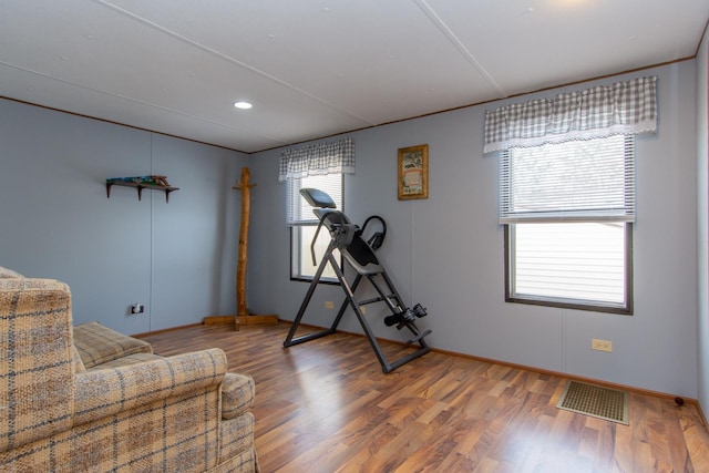 workout area with visible vents, baseboards, and wood finished floors