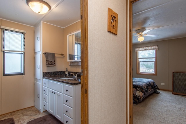 bathroom featuring ceiling fan, ensuite bath, vanity, and baseboards