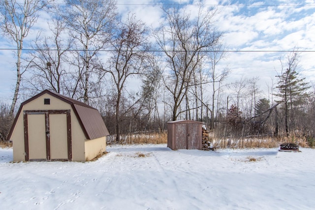 yard layered in snow featuring a storage shed and an outbuilding