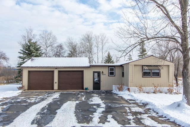 view of front facade with an attached garage, driveway, and metal roof