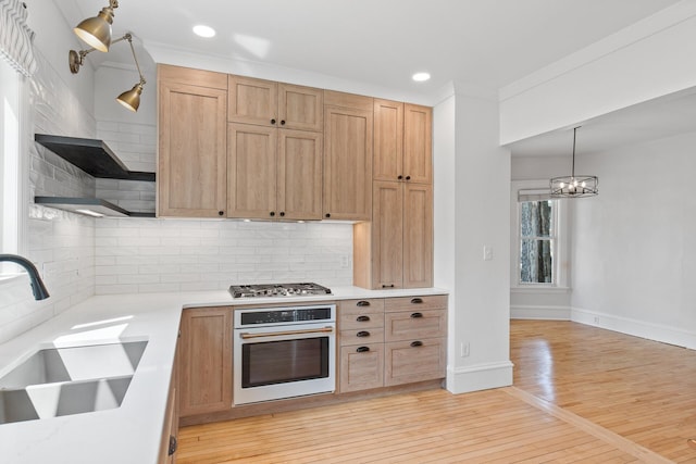 kitchen featuring a sink, light countertops, white oven, decorative light fixtures, and stainless steel gas stovetop