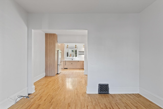 empty room featuring light wood finished floors and baseboards