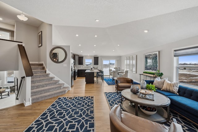 living room featuring light wood-type flooring, lofted ceiling, and a textured ceiling