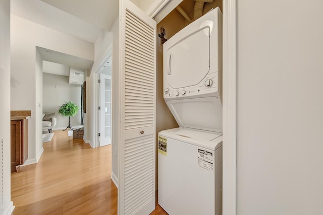 laundry room with light hardwood / wood-style flooring and stacked washer / dryer