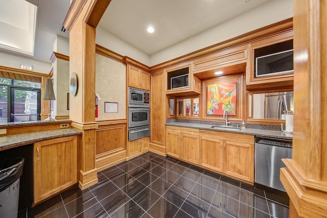 kitchen featuring sink, dark tile patterned floors, dark stone counters, and stainless steel appliances