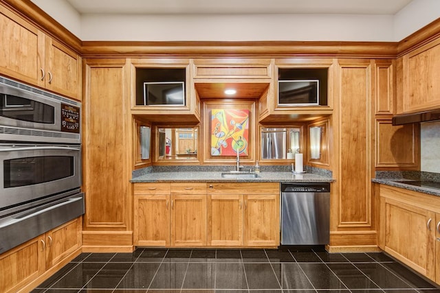 kitchen featuring sink, appliances with stainless steel finishes, dark stone countertops, and dark tile patterned flooring