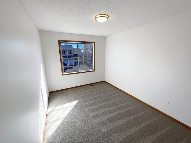 carpeted empty room featuring a textured ceiling