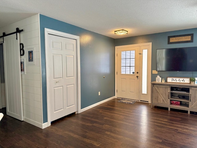 foyer with a barn door, dark hardwood / wood-style floors, and a textured ceiling