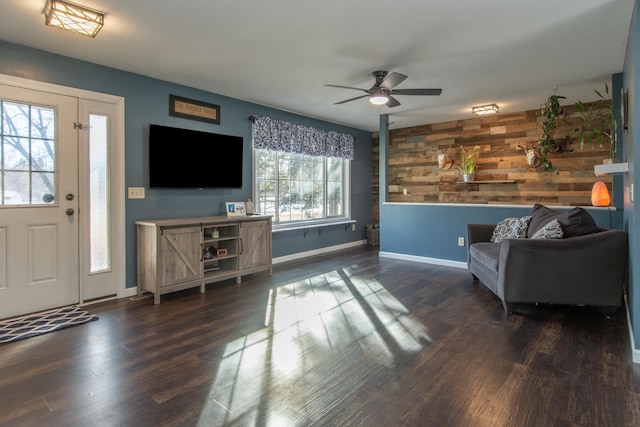 living room featuring dark wood-style flooring, baseboards, and a ceiling fan