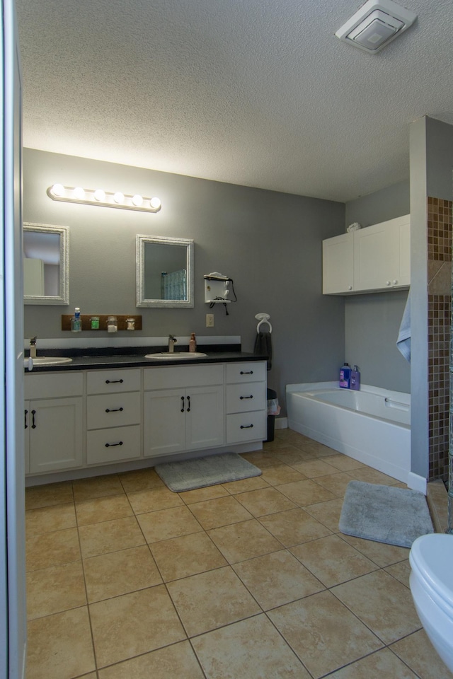 bathroom with visible vents, a bath, a textured ceiling, vanity, and tile patterned flooring