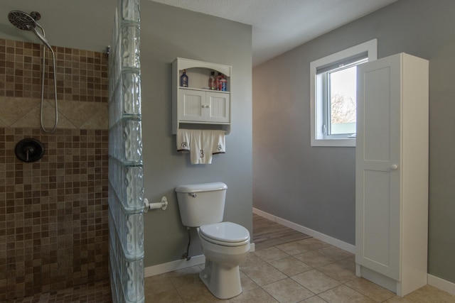 full bath with tile patterned floors, baseboards, a tile shower, and toilet