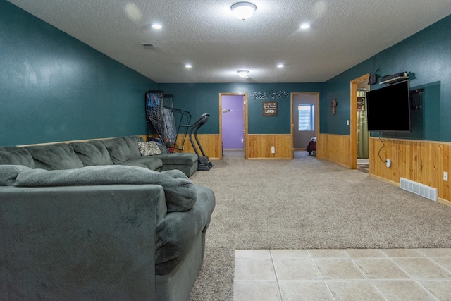 carpeted living room featuring visible vents, wainscoting, and a textured ceiling