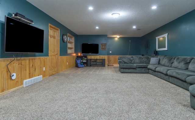 carpeted living room featuring visible vents, a textured ceiling, wooden walls, recessed lighting, and a wainscoted wall
