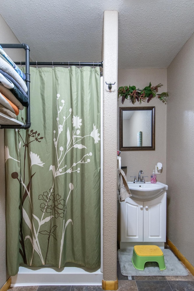 bathroom with baseboards, vanity, a shower with curtain, and a textured ceiling