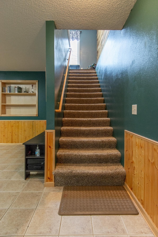 staircase with tile patterned flooring and a textured ceiling