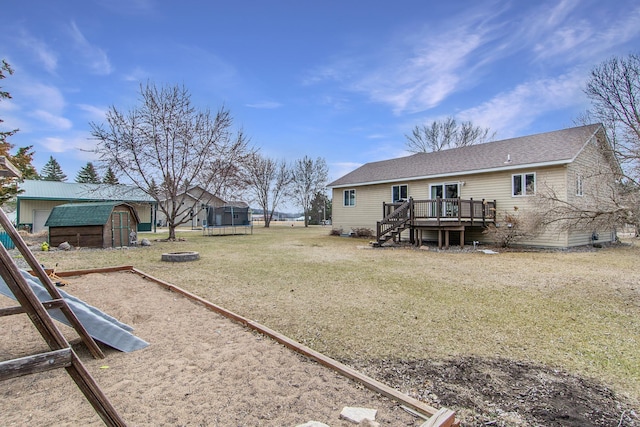 view of yard featuring an outbuilding, a storage unit, stairs, a trampoline, and a deck