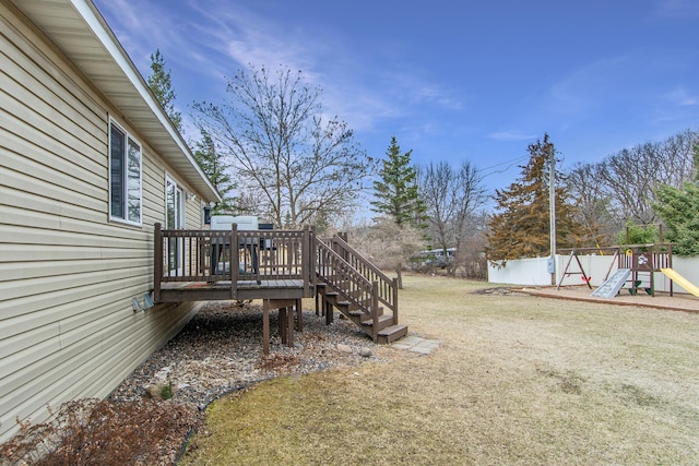 view of yard featuring fence, a playground, and a deck