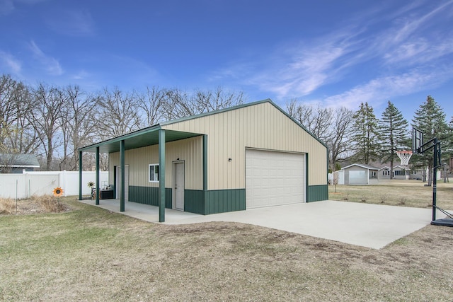 detached garage with concrete driveway and fence
