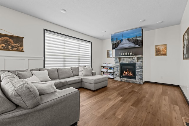 living area with a wainscoted wall, a fireplace, wood finished floors, and a decorative wall